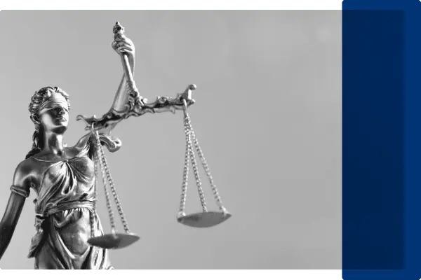 A black and white image of a lady justice statue carrying the scales.