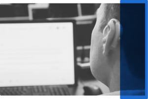 A man with a hearing aid at a laptop